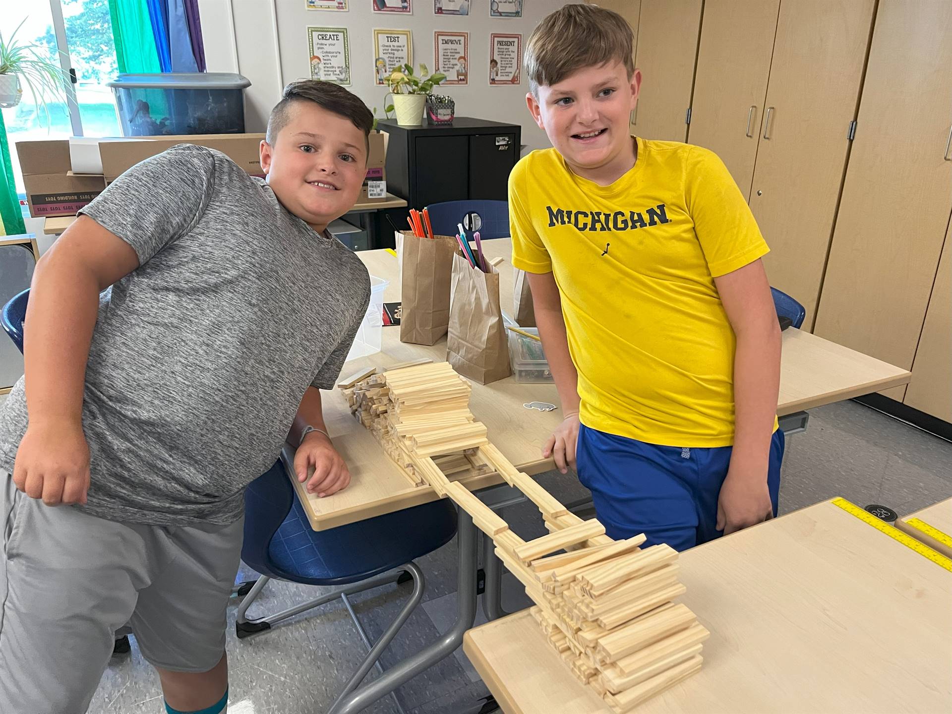 Students standing next to bridge they made